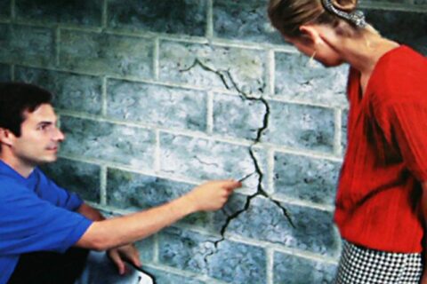 A Man showing a Crack in the wall at Waukesha, WI.