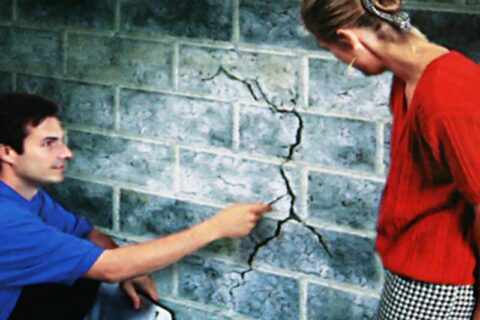 A Man showing a Crack in the wall at Waukesha, WI.